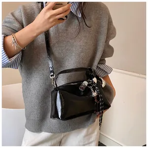 Detail der schwarzen glänzenden Boston-Tasche mit Perlenanhänger auf Freizeitoutfit
