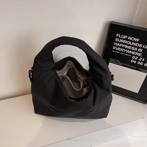 Quilted black nylon tote bag with striped lining on a minimalist marble surface