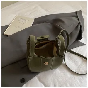 Olivgrüne Beuteltasche mit Kontrastnähten auf grauem Sakko im minimalistischen Urban-Stil