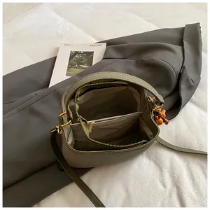 Sac seau vert olive en cuir grainé avec compartiments internes et pendentif en bois