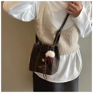 Detail einer dunkelbraunen Beuteltasche mit Kontrastnaht und Handschuh-Anhänger