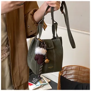 Detailaufnahme der dunkelgrünen Wildleder-Beuteltasche mit weißen Nähten und Anhänger