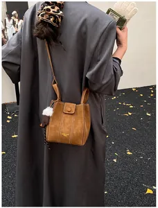 Detail der braunen Beuteltasche mit weißen Kontrastnähten und Plüschkugel-Anhänger