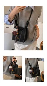 Details der schwarzen Beuteltasche mit weißen Kontrastnähten und Handschuh-Anhänger