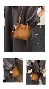 Detail der braunen Wildleder-Beuteltasche mit Kontrastnähten und Deko-Anhänger