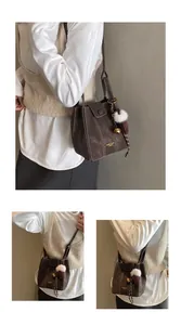 Detail der dunkelbraunen Eimertasche mit weißen Nähten und flauschigem Plüsch-Anhänger