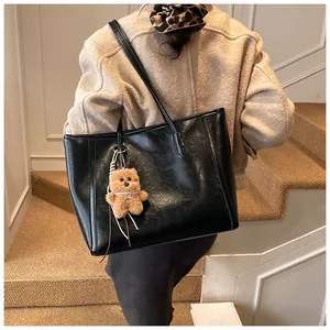 Détail du sac cabas en similicuir noir avec un charmant pendentif ours en peluche sur la bandoulière