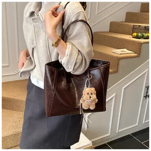 Détail du grand sac cabas en cuir marron foncé avec un petit ours en peluche décoratif