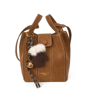 Braune matte Beuteltasche aus Leder mit weißen Nähten und Plüsch-Handschuh-Anhänger
