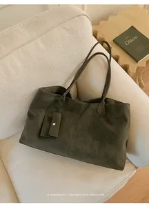 Detail view of deep olive green tote bag on sofa with matching small card pouch