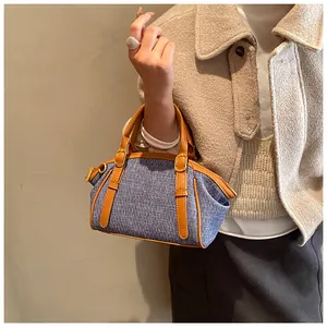 Detail view of denim and brown leather handbag with retro metal buckle on wool coat