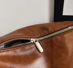 Détail de la fermeture éclair dorée lisse sur le sac en daim marron de style vintage chic