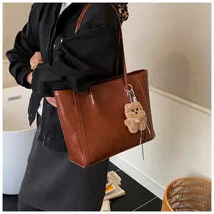 Détail d'un grand cabas vintage en similicuir marron avec un pendentif ours en peluche