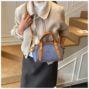 Detail of blue textured fabric handbag with brown leather trim and golden metal hardware