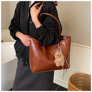 Détail du grand sac cabas vintage en cuir marron avec accessoire de charme ours en peluche