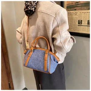 Detail showing the blue denim fabric texture and brown leather strap of the Boston bag