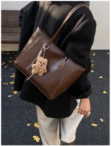 Détail du sac cabas marron foncé avec texture cuir brillant et pendentif ours en peluche