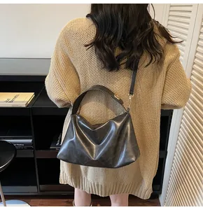 Détail du sac bandoulière demi-lune en suédine noire avec garnitures dorées élégantes
