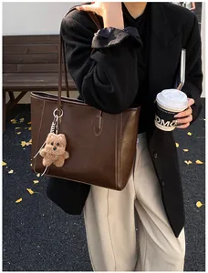 Détail du sac cabas en cuir marron foncé avec coutures vintage et breloque ours mignon