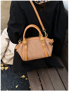 Rear view of brown woven crossbody bag with leather straps on a long black winter coat