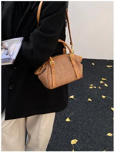 Brown canvas crossbody bag with tan leather trim and gold buckle shown in street style