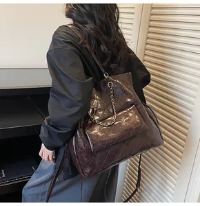 Dettaglio borsa tote in vernice marrone scuro con trama trapuntata e catena decorativa