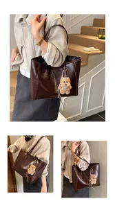 Détail du sac cabas marron foncé en cuir brillant avec pendentif ourson en peluche