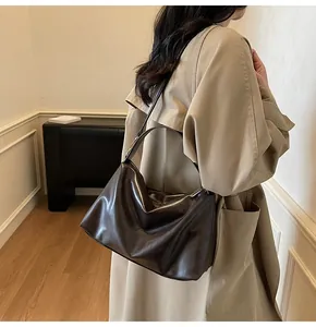 Détail d'un sac porté épaule en daim marron avec texture souple et plis sur un mannequin