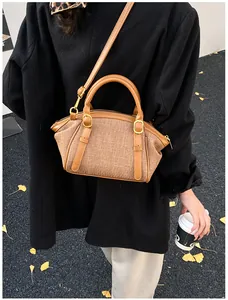 Close-up of brown woven texture handbag with leather straps worn as a crossbody bag