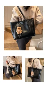 Détail d'un sac cabas en cuir noir brillant avec charmant ours en peluche marron et anses