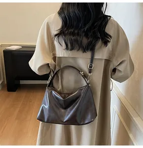 Détail d'un sac hobo en daim foncé avec texture souple et finitions métalliques dorées