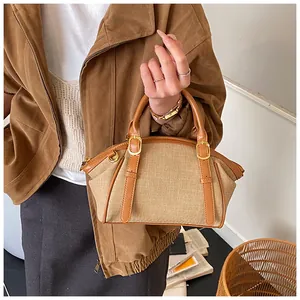 Detail of a retro canvas and brown leather crossbody bag with golden hardware and d-rings