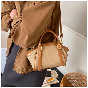 Close-up of retro canvas crossbody bag with brown leather handles and gold hardware