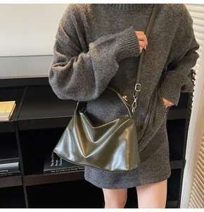 Gros plan du sac bandoulière en daim vert olive avec cuir texturé et sangle rétro chic