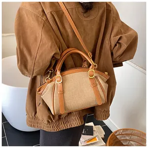 Close-up of a vintage beige canvas crossbody bag with brown leather trim on a model