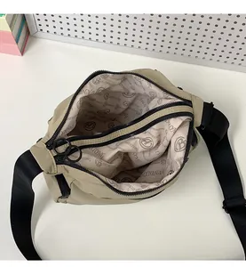 Detailed view of the khaki crossbody bag interior showing logo lining and black zippers