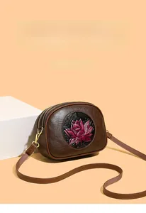 Close-up of embossed purple lotus flower design on brown leather Boston bag