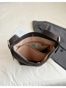 Top view of spacious brown leather bucket bag interior with zipper pocket and silver buckle