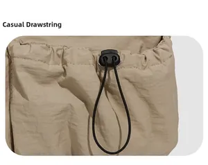 Détail du cordon de serrage réglable avec stoppeur noir sur le sac en nylon kaki