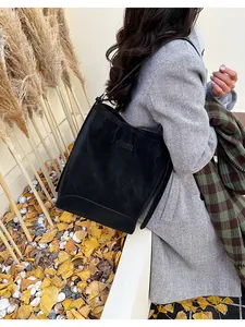 Detail shot of a black suede bucket bag with slim shoulder straps in an autumn setting