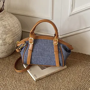 Retro blue denim crossbody bag with brown leather trim and gold metal buckle on magazine