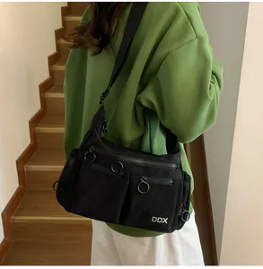 Close-up of black canvas crossbody bag with multiple zip pockets and metal rings