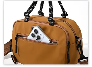 Detail of the yellow nylon bag showing a front zipper pocket with a smartphone inside