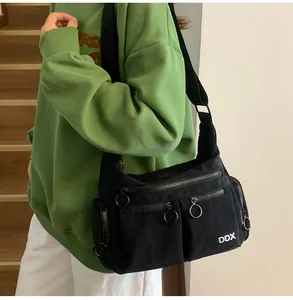 Detail view of large metal ring zippers and multi-pocket design on black crossbody bag