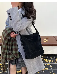 Chic black suede shoulder bucket bag styled in an autumn street scene setting