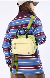 Detail of knot handle and green strap on a yellow crossbody bag worn by a model
