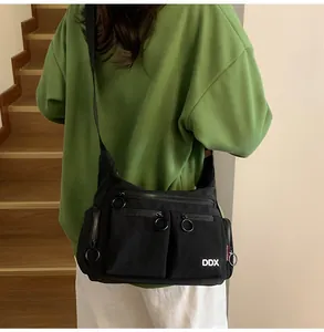 Close-up of a black multi-pocket crossbody bag with ring zippers and white DDX logo detail