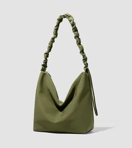 Macro view of olive green hobo bag featuring pleated shoulder strap and nylon texture