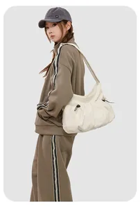 Détail du sac croissant en nylon blanc cassé montrant les plis et la boucle de réglage noire