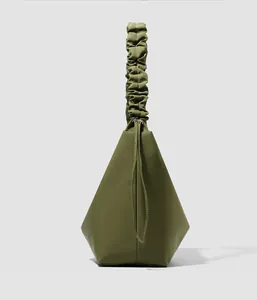 Detail of dark green geometric handbag featuring a trendy ruched handle and matte leather